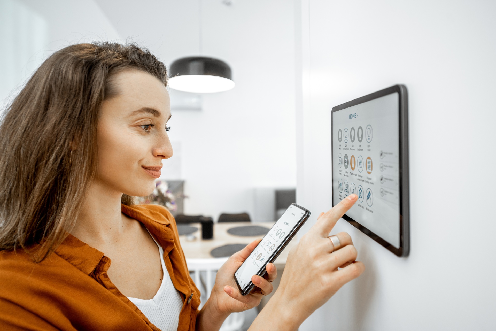 Frau nutzt Wanddisplay zur Steuerung von Smart-Home-Funktionen | Fronius Speicher Wechselrichter